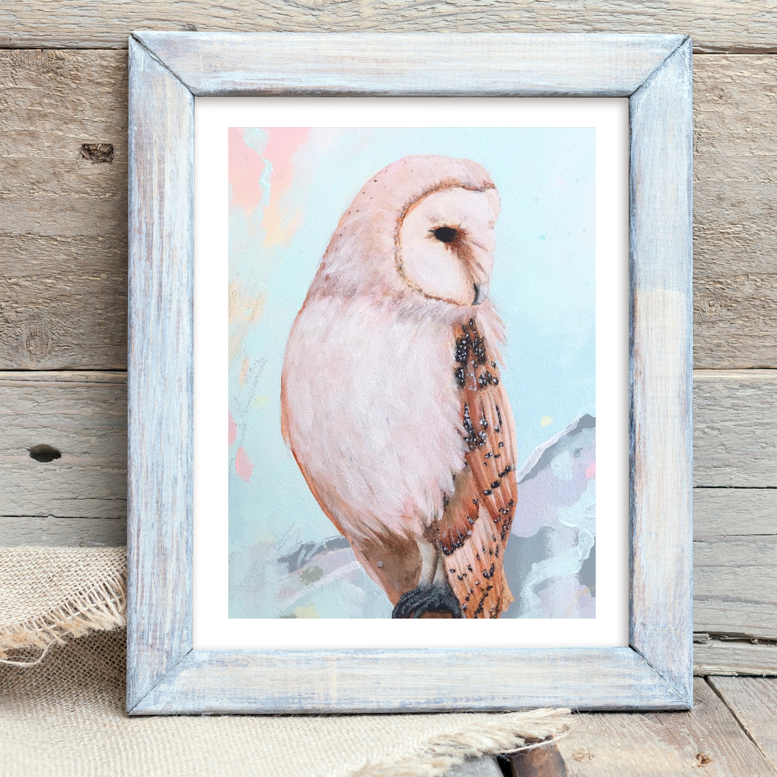 Framed artwork of an owl on a wooden surface